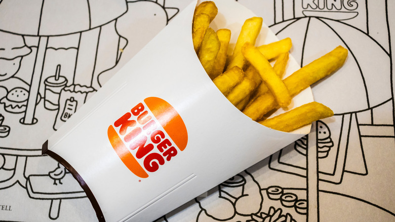 A carton of Burger King fries, sitting against a cartoon background