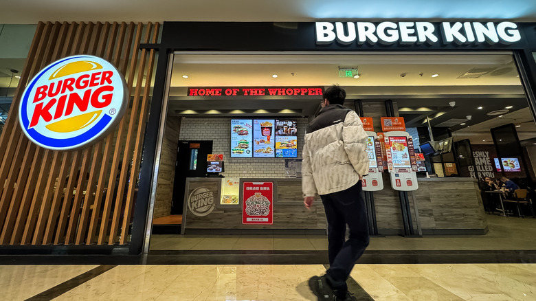A man is seen standing outside a Burger King restaurant in a shopping mall