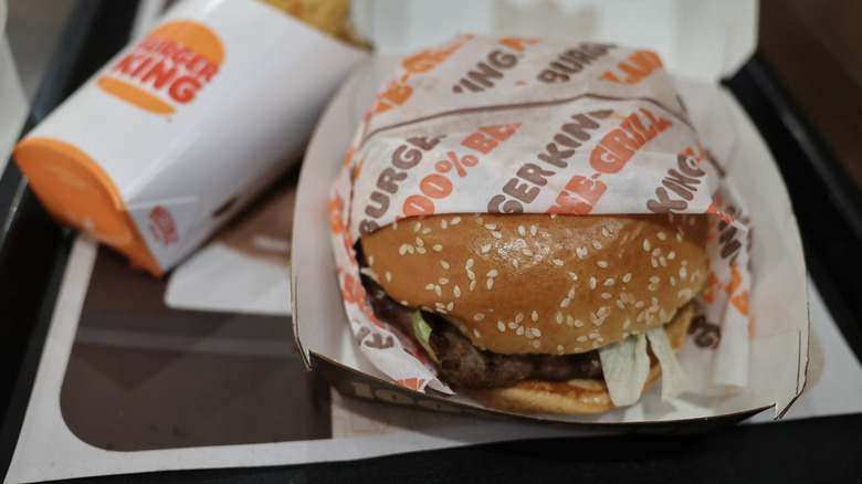 A new Burger King Whopper is seen in its wrapper, next to a carton of fries