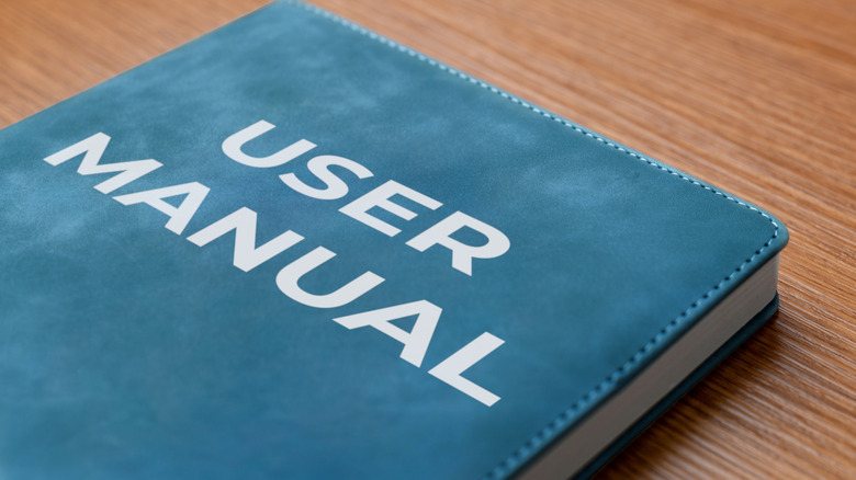 A blue leatherbound book that reads "user manual" on a wood table