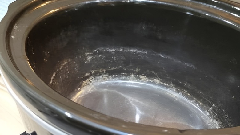 A close-up of a Crockpot with white residue in the ceramic insert