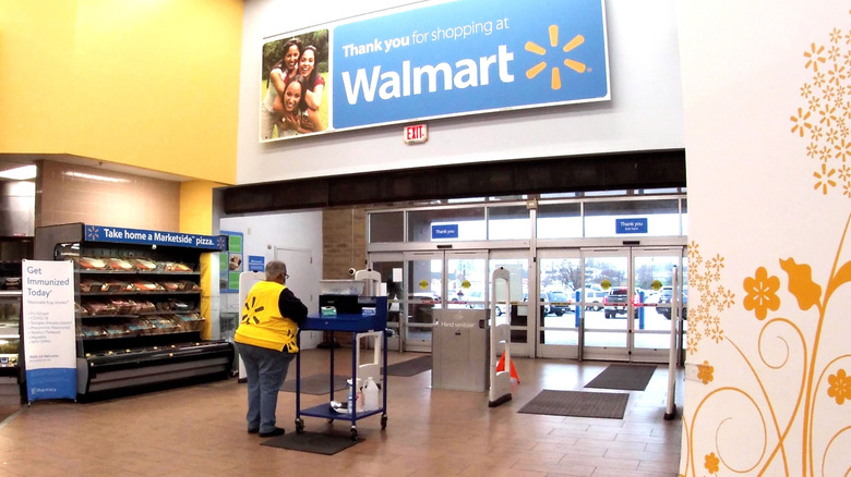 Walmart door greeter in yellow vest standing next to entrance