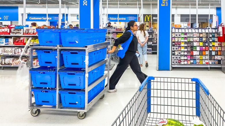 Walmart associate pulling pickup order cart behind them as they walk in front of regular cart
