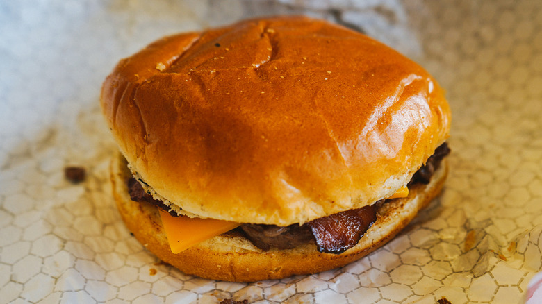 A bacon cheeseburger from Wendy's is unwrapped on a table.