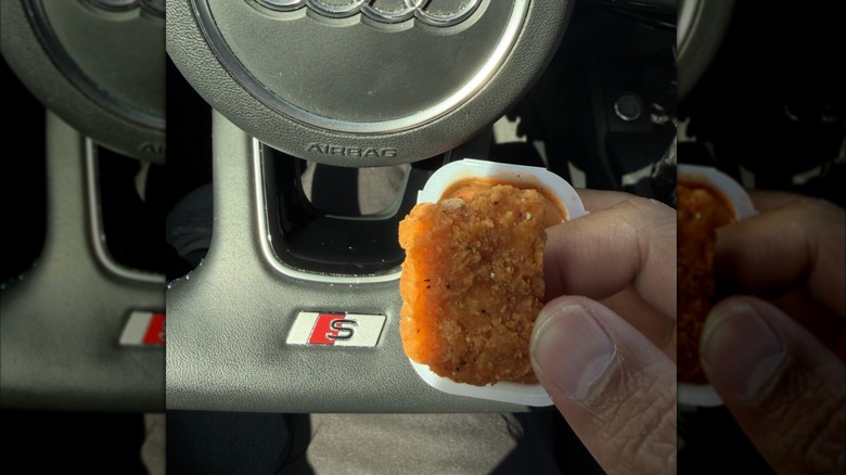 A hand is holding a small Wendy's chicken nugget.