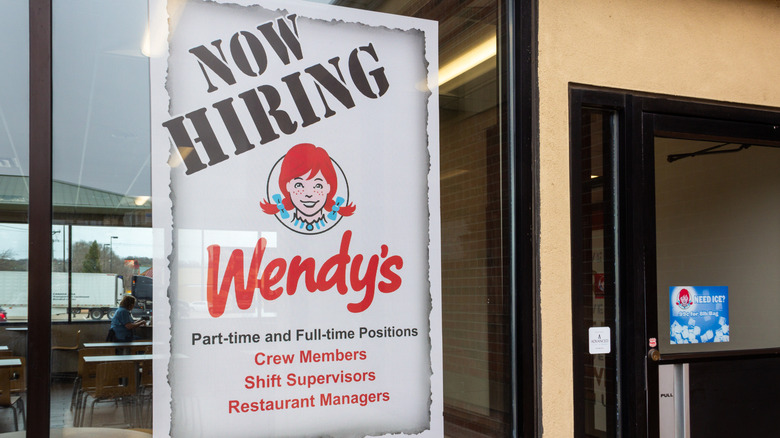 A Wendy's restaurant displays a "Now Hiring" sign in its window.