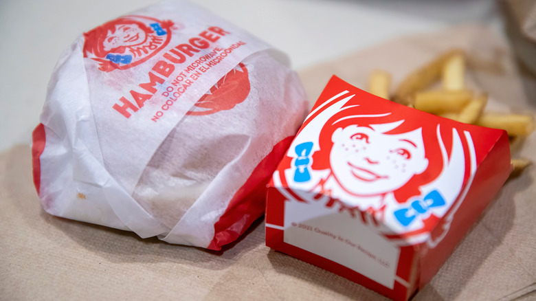 A Wendy's hamburger and fries sit on top of napkins.