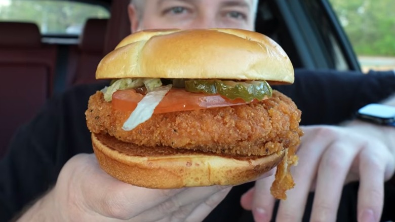 A man holds up a Wendy's Spicy Chicken Sandwich.