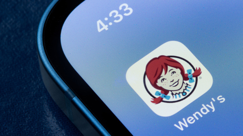 A smartphone is open to the Wendy's app icon.