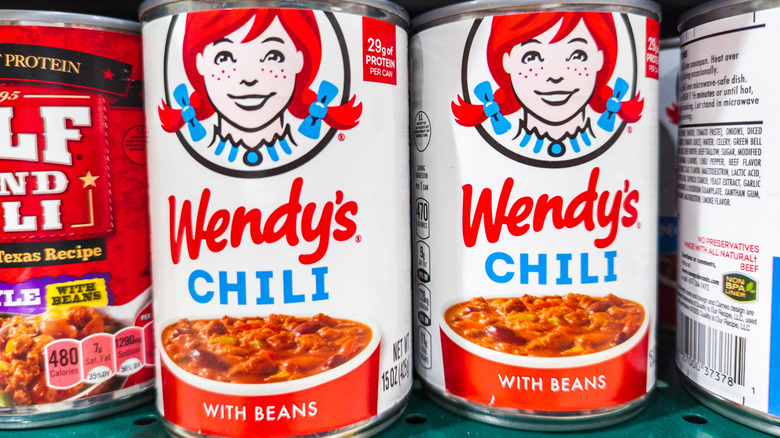 Cans of Wendy's chili are on a store shelf.