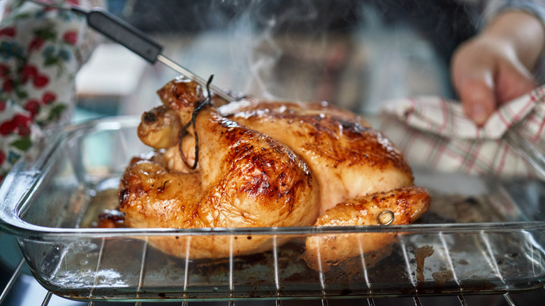 A whole chicken in a baking dish placed on an oven rack