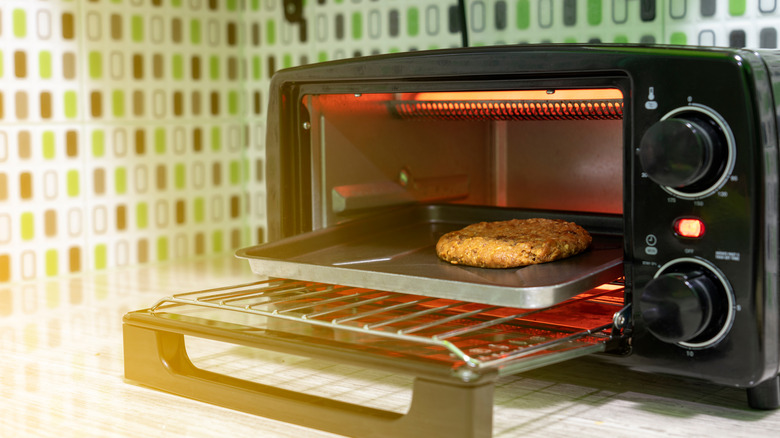 A single cookie on a baking tray inside a toaster oven