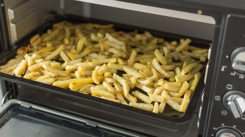 A baking tray full of fries inside a toaster oven