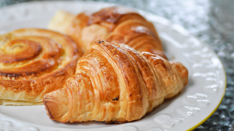 Croissants and a cinnamon roll on a white plate