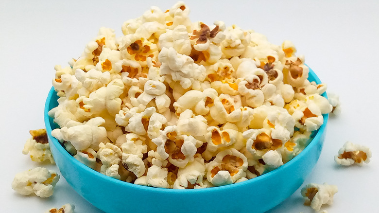 A blue bowl full of popcorn on a white table
