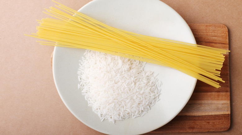 A plate full of raw rice and spaghetti on a wooden table