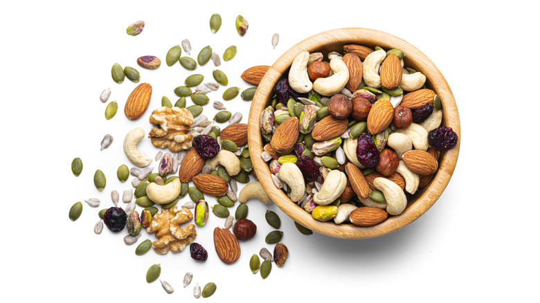 Various types of nuts and seeds in a bowl and on a white table