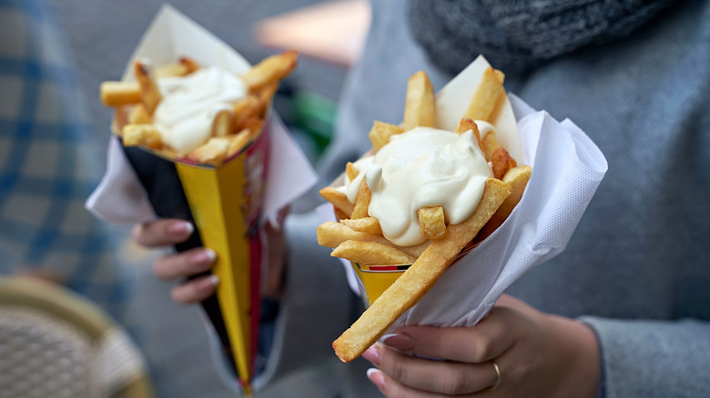 Woman holding a cone of Belgian fries in each hand