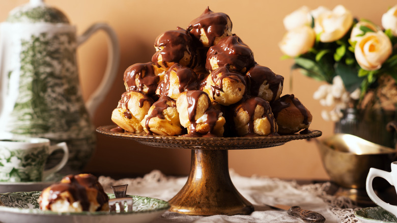 A pile of chocolate-drizzled profiteroles on cake tray