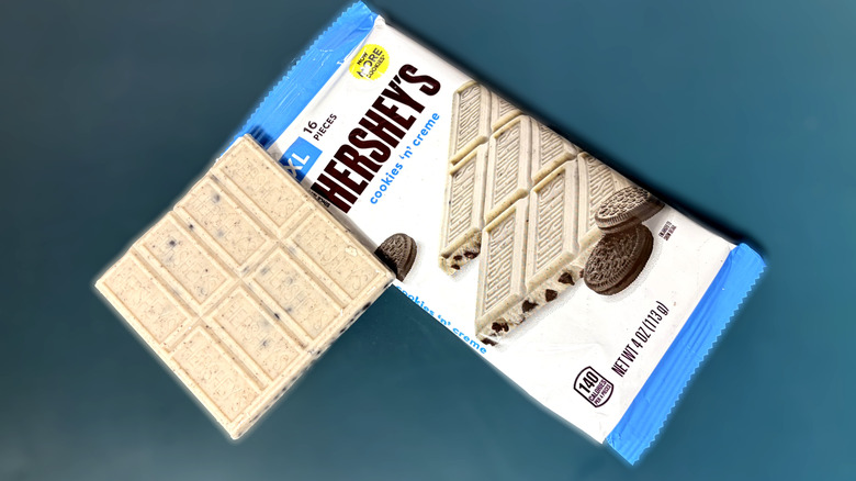 Piece of Hershey's cookies and cream bar in next to packaged bar