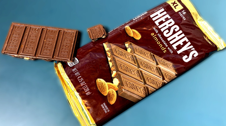 Pieces of Hershey's almond chocolate bar in next to packaged bar