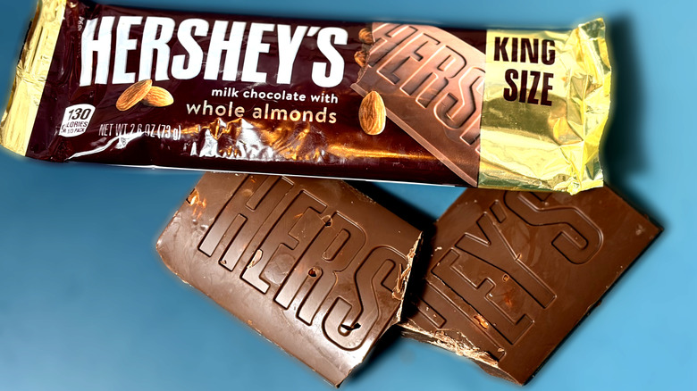 Hershey's almond chocolate bar broken in half next to packaged bar