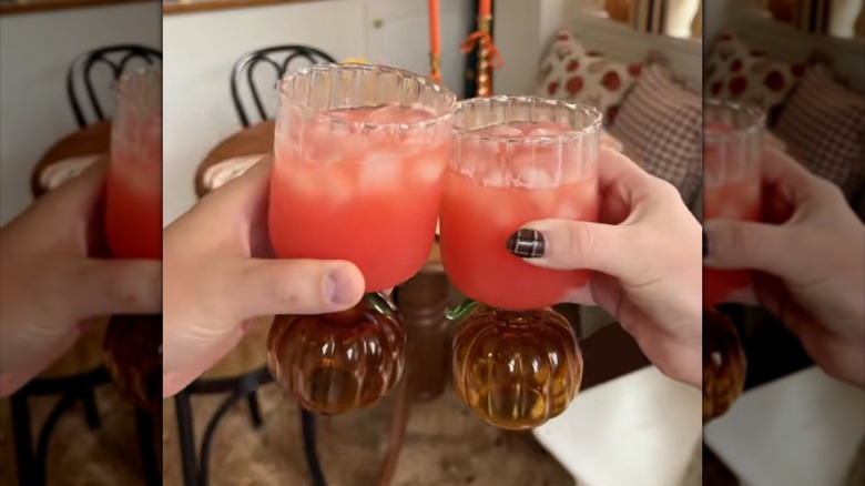 Two people toasting drinks in pumpkin-shaped stemware