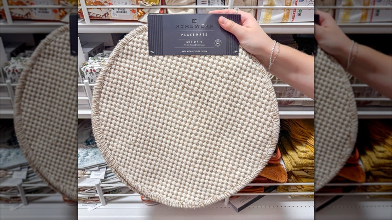 Hand holding up round woven placemat in HomeGoods