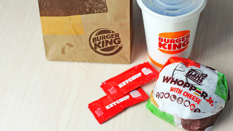 Burger King's Whopper Jr., ketchup, beverage, and paper bag on a table
