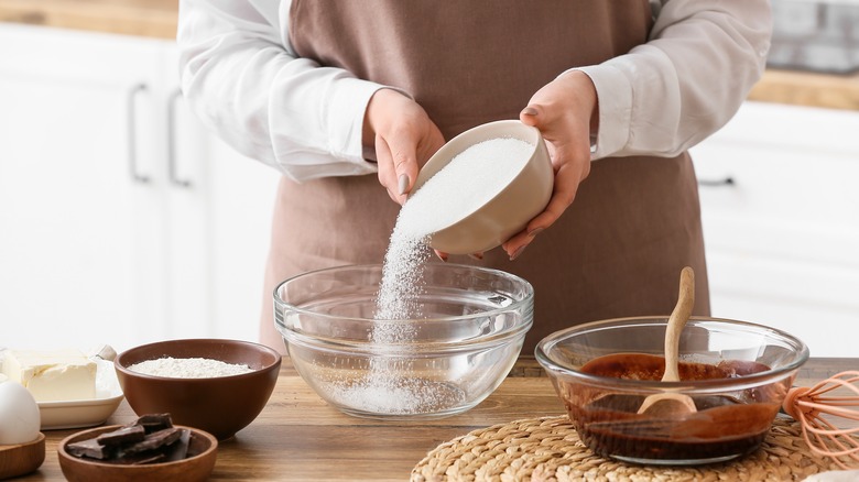 Person pouring sugar into bowl
