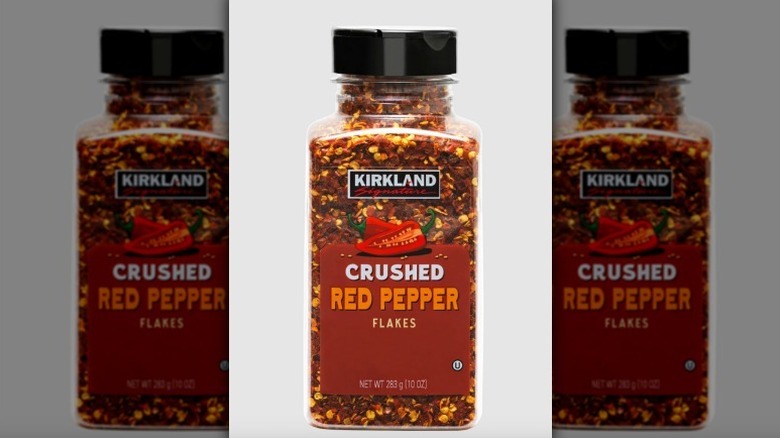 Jar of crushed red pepper on white background