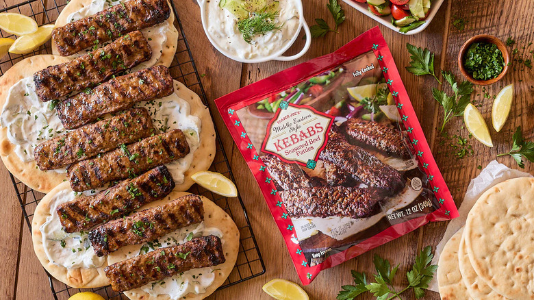 Middle Eastern kebabs with pitas on a wooden board, next to a bag of Trader Joe's Middle Eastern Style Kebabs