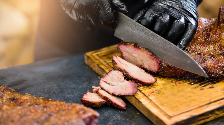 gloved hands slicing brisket