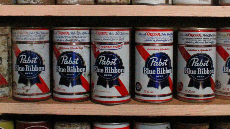 A row of vintage Pabst Blue Ribbon cans, some beginning to rust, on display