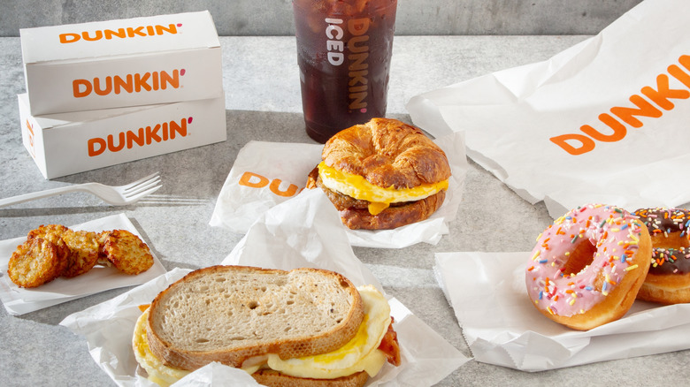 A variety of breakfast items from Dunkin' outside of their bags on a grey table