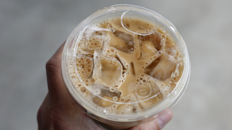 A hand holds a Dunkin' iced coffee, seen from overhead