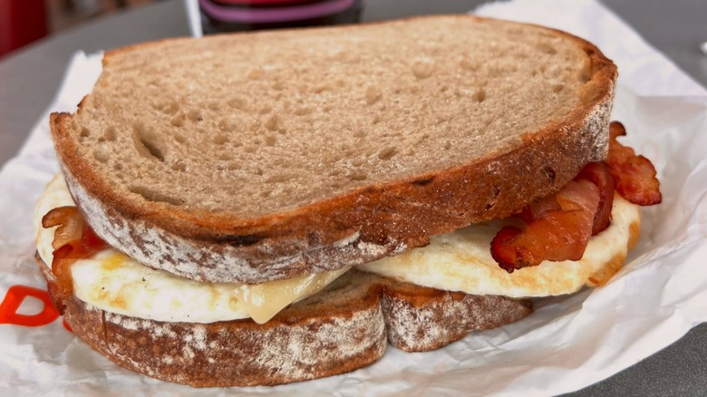 A Dunkin' breakfast sandwich, with eggs and bacon on sourdough bread