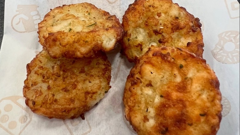 A close-up of four Dunkin' hash browns on branded paper