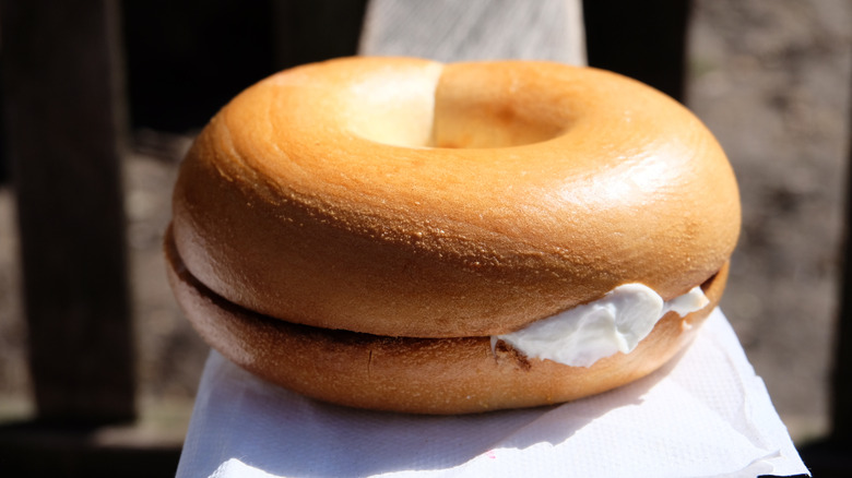 A bagel with a cream cheese filling on a paper napkin