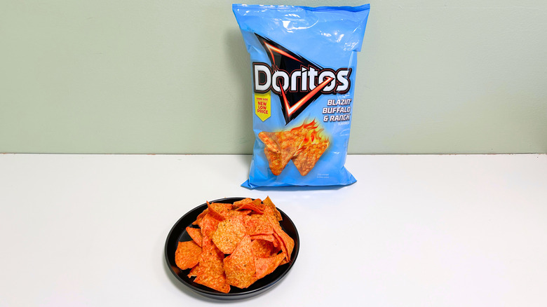 A bag of Doritos Blazin' Buffalo and Ranch next to a black plate of chips