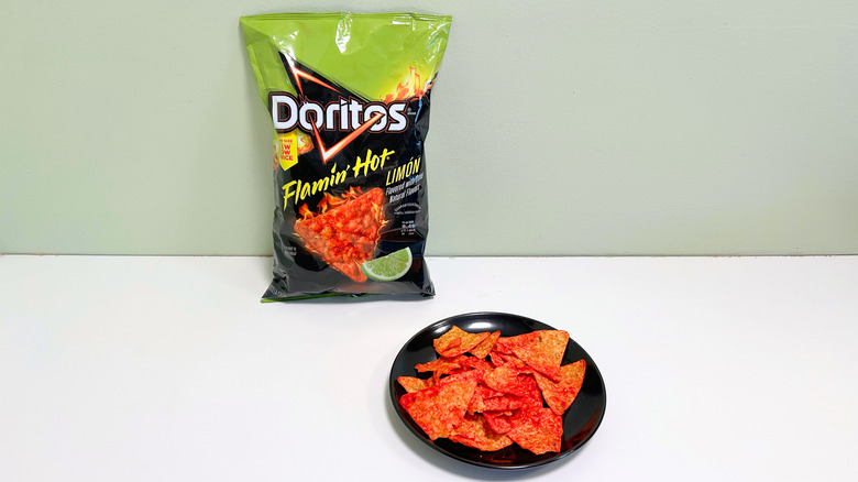 A bag of Doritos Flamin' Hot Limon next to a black plate of chips