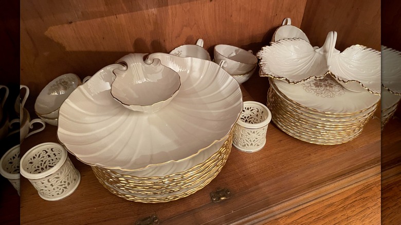China on a shelf in the Lenox Orleans pattern, including plates and serving dishes