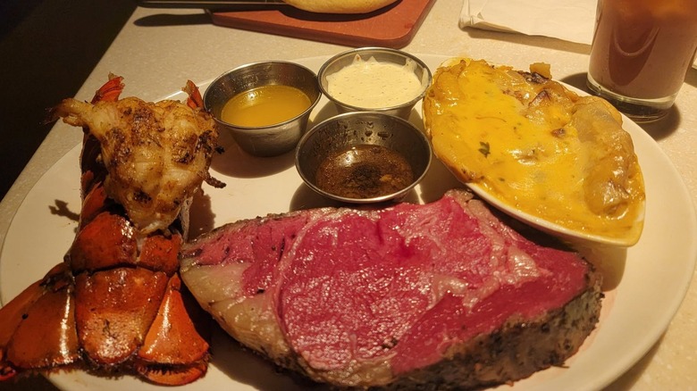Firebirds' prime rib and lobstertail meal with cheesy potatoes and ramekins of sauce