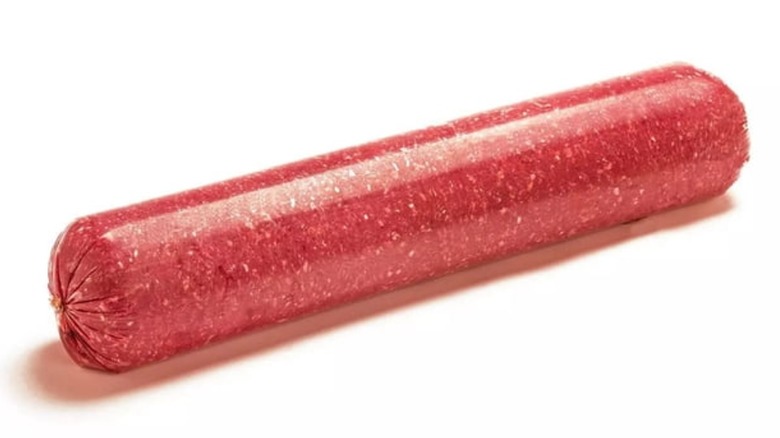 A meat log made of ground beef wrapped in plastic isolated on a white background