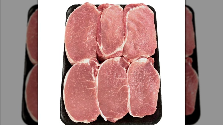 Raw pork chops layered on a white background with a mirror border