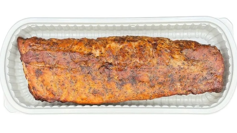 Baby back ribs in a clear plastic container on a white background