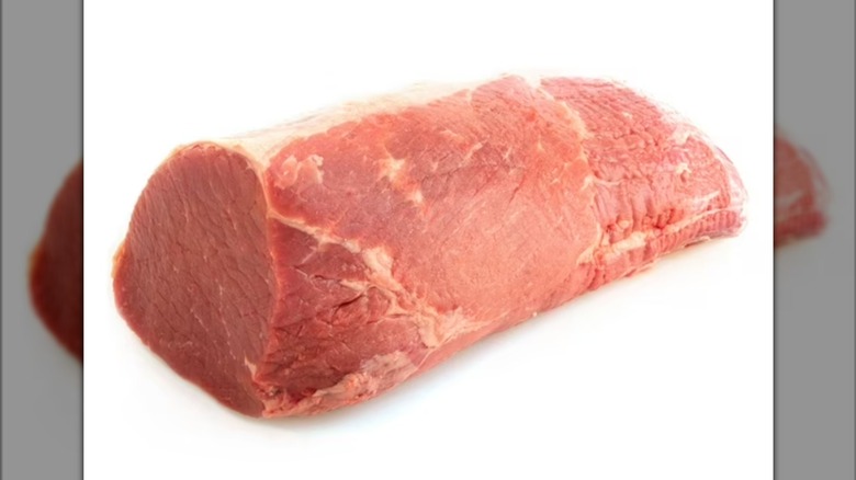 An angus beef eye of round roast, raw, isolated on a white background with a mirror border