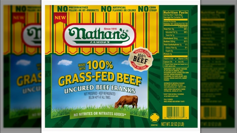 A package of Nathan's Famous all-beef, grass-fed, uncured hot dogs on a white background with a mirror border