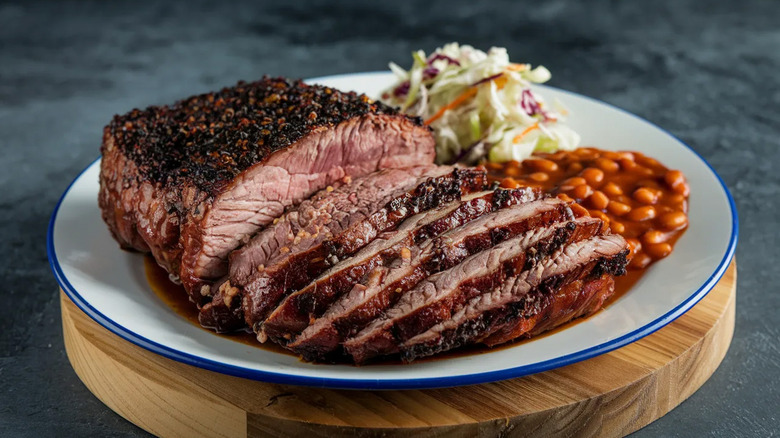 A plate with sliced brisket, baked beans, and coleslaw