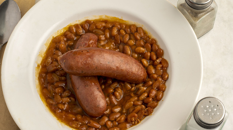 Two kielbasa on top of a bowl of baked beans